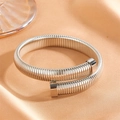 Detail of silver Tubogas spiral flexible bracelet on orange silk background - Steel Plain Bangle (R208)