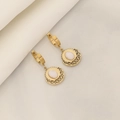 Detail of gold hollow-out earrings with white oval stone on soft fabric background - White Jade Earrings