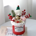 Dettaglio di una confezione regalo di Natale con orsetto, renna e decorazioni festive - Orso con cappello verde (con luce + sacchetto regalo)