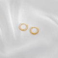 Detailansicht goldener Creolen mit weißer Spiralstruktur auf weißem Seidenstoff - Weiß