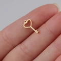 Close-up of a tiny golden heart-shaped key pendant held to show its actual size for DIY - Key / Gold