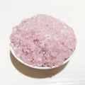Close-up of natural pink crystal gravel stones inside a white ceramic bowl - Rose Quartz