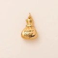 Golden metal drawstring bag pendant with FAIRY DUST engraving on beige background - Money Bag