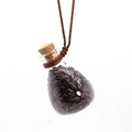 Detailed macro view of a glass pendant with dark red natural stone chips and cord - Garnet
