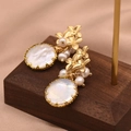 Baroque freshwater pearl earrings with gold floral details on a vintage wood display - Three Flowers Edging Style