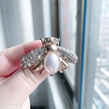Golden bee brooch with sparkling rhinestones and white pearl held by hand - Classic Gold Base Pearl Rhinestone Style
