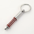Macro shot of chrome-plated shock absorber keychain with vibrant red spiral spring detail - Red