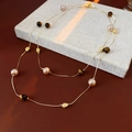 Detail einer Goldkette mit rosa Perlen und braunem Tigerauge auf einem Buch - Gold