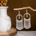 Detailed view of silver hoop tassel earrings hanging on a natural wooden stand - Silver Round Tube Tassel(E2875-19)