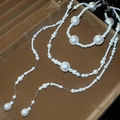 Detail of multi-layer pearl necklace on brown velvet display with elegant silver links - White