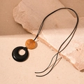 Détail du pendentif en résine ambrée marbrée et anneau noir sur socle roche - Collier Rond en Résine Marron