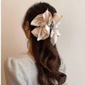 Elegant beige satin oversized bow hair claw clip styled on back of model hair - Champagne