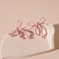 Close-up of pink lacquered bow stud earrings on a minimalist decorative stone base - Pink Bowknot (Silver Needle)