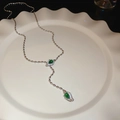 Detail view of Y-shaped necklace with green pear-cut stones on a white ceramic tray - Green Zircon Snake Head Style