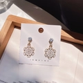 Detail shot of golden snowflake earrings with white enamel and sparkling zircons - Snowflake