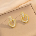 Nahaufnahme goldener Herzohrringe mit Zirkonia-Mikropavé auf Seidenhintergrund - Gold Ohrstecker (8895)
