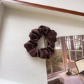 Close-up van een donkerbruine satijnen scrunchie met zijdeachtige textuur en plooien - Klein / Donker Koffie
