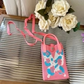 Détail du tissage du sac bandoulière rose à motif animalier sur une table en verre chic - Papillon Bleu et Blanc - Sac de Téléphone