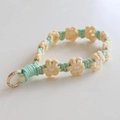 Detail of handmade woven daisy strap with green braided cord and golden metal ring - Milk Yellow