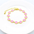 Gold plated link bracelet featuring pink enamel smiley face charms on a white plate - Pink