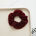 Detailed view of dark red scrunchie made of shiny fabric placed on a beige tray - Burgundy