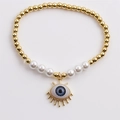 Detail of beaded evil eye bracelet with golden metal beads and white pearls on plain background - Light Blue