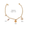 Golden bracelet with natural pearl, orange slice, and shell charms on white background - Shell Pearl Style