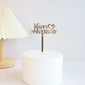 Golden acrylic Happy Anniversary cake topper on a minimalist white cake display - Anniversary Heart / Gold