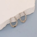 Macro detail of twisted silver stainless steel hoop earrings on white stone background - Silver Twisted Spiral Hoop
