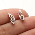 Silver butterfly wing stud earrings in stainless steel displayed on fingertips - 673 Hollow Butterfly Wing / Silver
