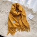Ginger yellow tassel cashmere scarf draped on a soft textured beige background - Turmeric