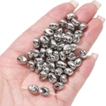 Detailopname van glanzende zilveren CCB-stervormige kralen die in een hand worden gehouden - Gedraaid Ovaal 7x8mm (20 stuks/pak)