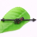 Macro shot of black industrial barbell with skull hand and red rhinestones on green leaf - Black Skull Hand Red Zirconia Spike