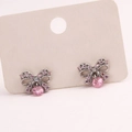 Detail view of silver bow stud earrings with pink crystals on a display card - Style 2-Silver