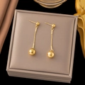 Macro detail of gold-plated spherical drop earrings with snake chain on jewelry display - Double Ball Long Drop Earrings (EHG266) / Gold