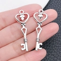 Detail of silver alloy heart skeleton key pendants held by hand to show the actual size - Heart Hollow Key (6709)