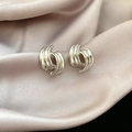 Detail view of silver geometric intertwined spiral earrings on champagne satin background - Silver