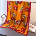 Detail of silk scarf with orange gold base and peony print draped on a table - 180*80cm / Orange Peony