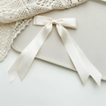 Detailed macro view of the cream white satin ribbon texture and smooth silk finish of the bow - Milky White