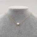 Collana minimalista con pendente a perla singola e catena sottile dorata su manichino - Perla Singola da 6MM