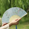 Traditional Chinese folding fan in light blue with peach blossoms and blue tassel - Bird Seeking Flower Branch
