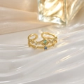 Macro shot of gold crown ring with blue stones on a white textured background - Blue Crown Open Ring (JZ0134)