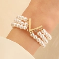 Three-layer faux pearl bracelet featuring a gold V-shaped charm on a model's wrist - Three Layer Pearl V Letter Pendant (5224)