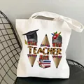 White canvas teacher tote bag with colorful educational graphics on a metal chair - Style C5