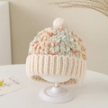 Detail van gebreide wintermuts met veelkleurig gemengd garen en een beige pluizige pompon - Eén maat / Beige