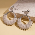 Macro detail of beige leather wrapped round earrings with silver studs on stone - White