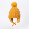 Close-up of yellow knitted winter hat for kids with soft fleece lining and fluffy pom-pom - S / Yellow
