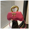 Close-up of pink PU leather handbag with golden metal handle and a bow detail - Pink