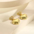 Détail de boucles d'oreilles cœur dorées avec zircons incrustés et motifs gravés polis - Style Coeur Or