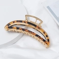 Close-up of golden metal arch hair claw with tortoiseshell acetate on white silk - Amber